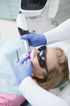 Vertical close up of a woman having her teeth scanned by professional dentist