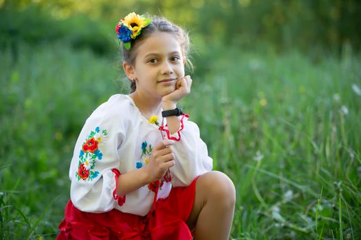 A little Ukrainian and Belarusian girl in an embroidered shirt on a summer background.