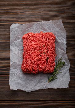 Fresh raw minced meat from ground beef or pork on cutting board and dark brown rustic wooden background from above for catalog or shop