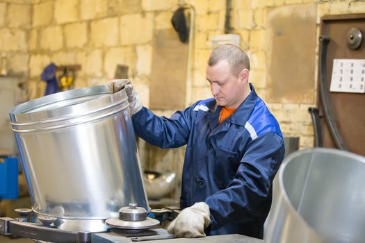 The worker at the factory makes ventilating metal pipes