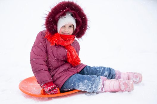 Child in winter. The girl is sledding.