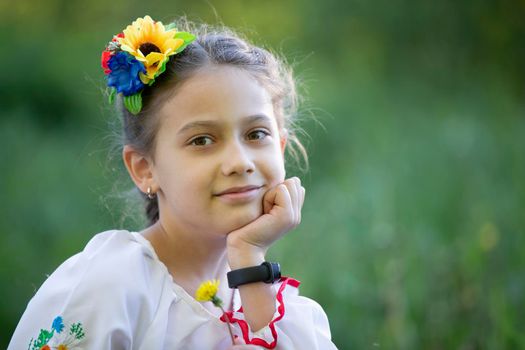 A little Ukrainian and Belarusian girl in an embroidered shirt on a summer background.