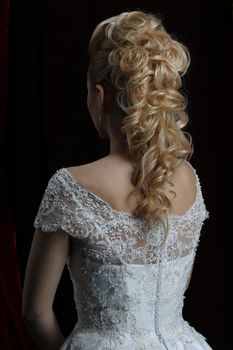 Blonde beauty hairstyle behind on a dark background beautiful.The long hair of the bride is neatly styled.