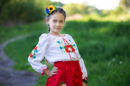 A little Ukrainian and Belarusian girl in an embroidered shirt on a summer background.