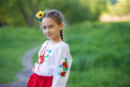 A little Ukrainian and Belarusian girl in an embroidered shirt on a summer background.