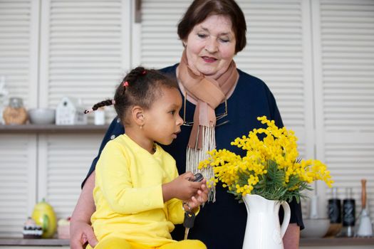 Grandmother and granddaughter from different races. The fair-skinned grandmother plays with the dark-skinned granddaughter.