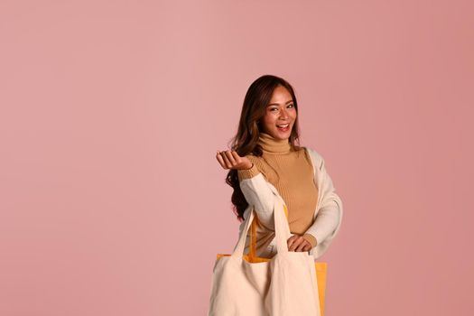 Beautiful woman holding shopping bags standing over pink background. Black Friday, sale, shopping concept.