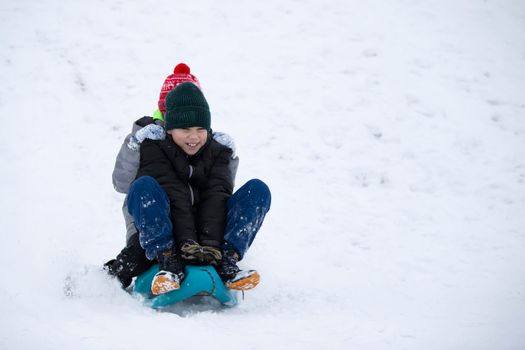 Children in winter. Boys friends are sledding.