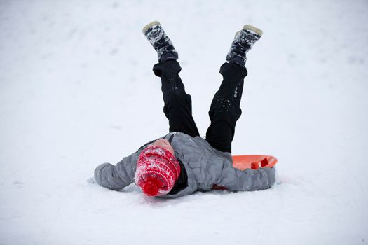 Child in winter. The boy is sledding.