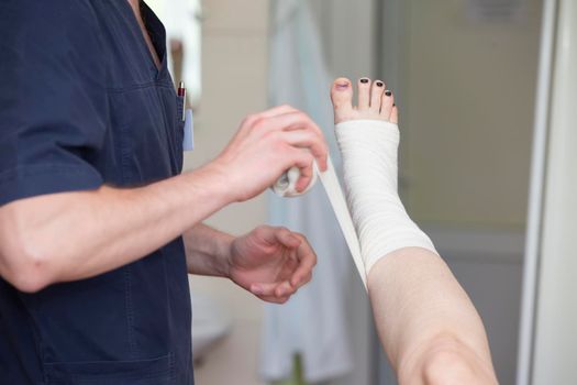 The doctor bandages the patient's leg. Surgeon and patient after vein surgery.