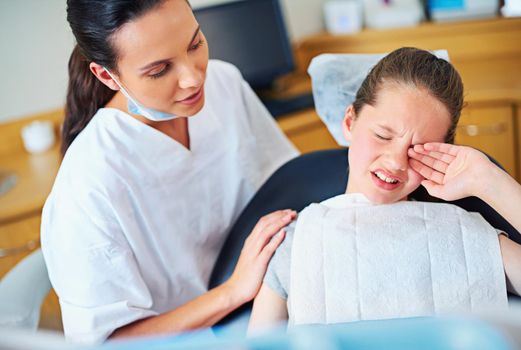 Everybody gets a cavity at some point. a crying little girl sitting in a dentists chair