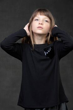 Portrait of a beautiful pensive teenage girl on a gray background.