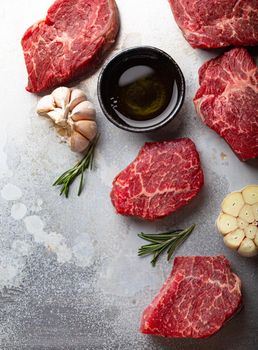 Raw uncooked meat beef cubes for stew or roasting with seasonings, olive oil, garlic and fresh rosemary on rustic aluminum baking tray from above