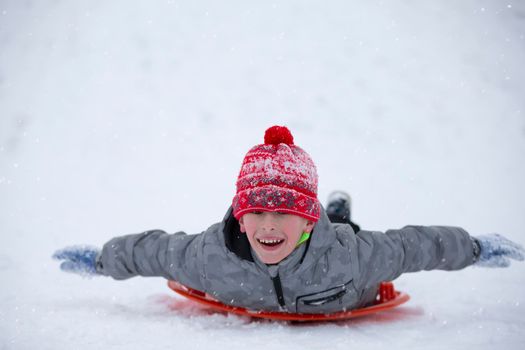 Cute young boy smiling while he is sledding