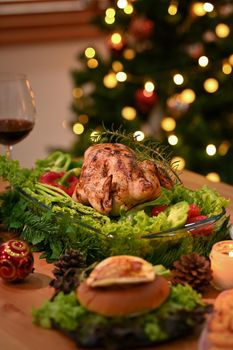 Roasted Thanksgiving Day turkey and glass of red wine on wooden table in decorated room with a Christmas tree.