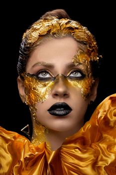 Fashion art Golden skin. Model girl with festive golden glamorous shiny professional make-up. Gold jewelry, bijouterie, accessories. Beautiful golden metallic body, black lips and skin.