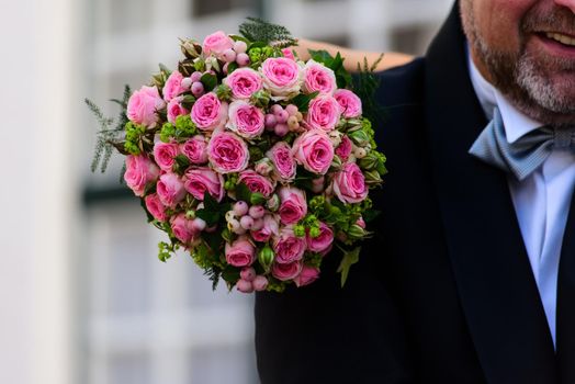 closeup of a a wedding bouquette of roses resting on the shoulder of the groom