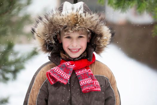 Funny little boy among the snow-covered Christmas trees. Child in winter.