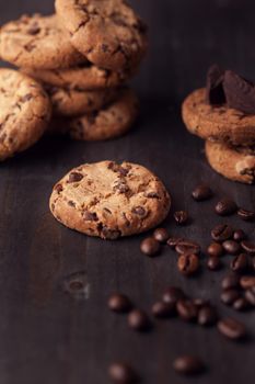 Chocolate chip cookies on old wooden table with coffee beans. Homemade snack.