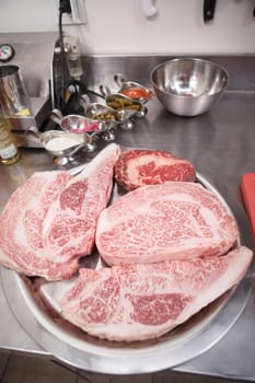 Vertical close up of fresh raw marbled beef steaks on a plate