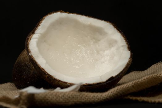 fresh coconut on black background drawing its water, raffia cloth