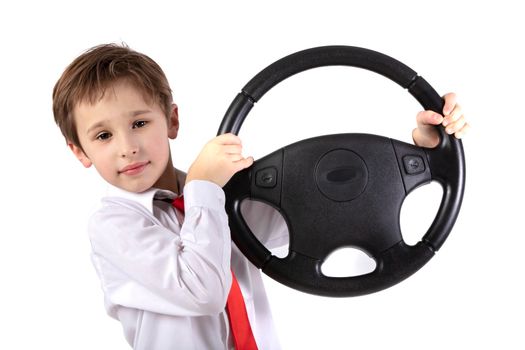 Funny little boy is holding a car steering wheel. Young driver on a white background.