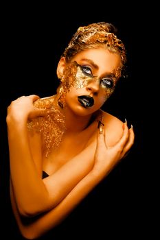 Fashion art Golden skin. Girl Model with Festive Golden Glamor Brilliant Professional Makeup. Creative makeup with golden foil.