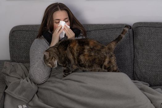 young brunette girl with long hair, sick lying on the sofa in her house taking medicine and an infusion