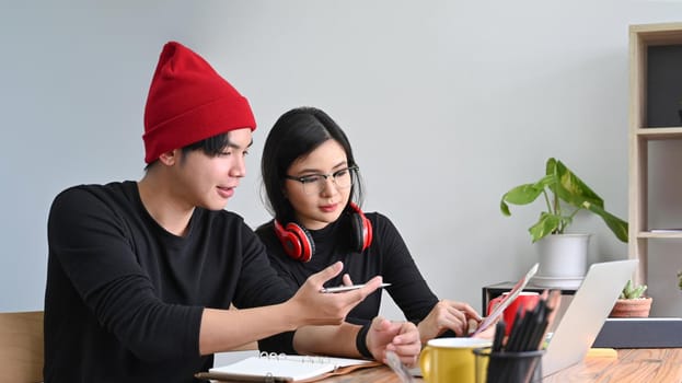 Two creative colleagues working on project together in office.