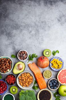 Selection of healthy products and superfoods: salmon, fruit, vegetables, berries, goji, spirulina, matcha, quinoa, chia, nuts with copy space. Clean eating concept, gray background, top view, close up