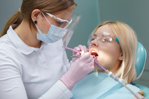 Young woman wearing protective glasses while dentist examining her teeth