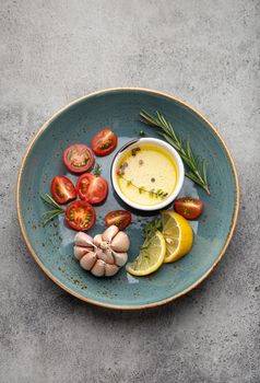 Food cooking fresh ingredients, healthy vegetables, herbs, spices, olive oil arranged on beautiful rustic blue ceramic plate from above