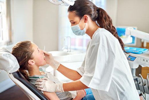 Checking for cavities. a young girl having her teeth examined by her dentist