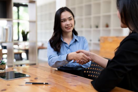 Portrait young asian woman interviewer and adviser shaking hands for a job interview. Business people handshake in modern office. Greeting deal concept.