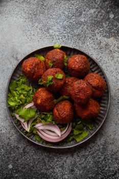 Traditional Middle eastern dish falafel served with fresh green cilantro and onion salad. Arab or Mediterranean appetizer falafel served on rustic background table. Top view.