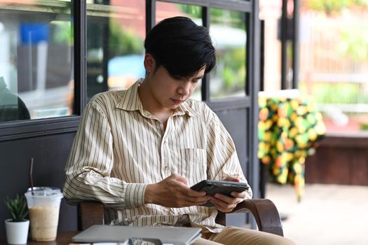 Handsome businessman sitting outdoor cafe and using smart phone.