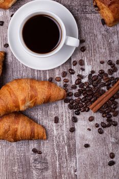 Cup of hot coffee and freshly baked croissants on dark wooden table. Tasty croissant.