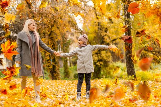 happy family: mother and child little daughter play cuddling on autumn walk in nature outdoors. High quality photo