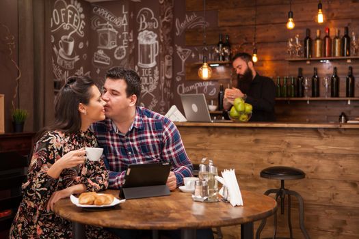 Happy couple using digital tablet while having coffee at restaurant. Hipster restaurant.