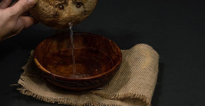 fresh coconut on black background drawing its water, raffia cloth