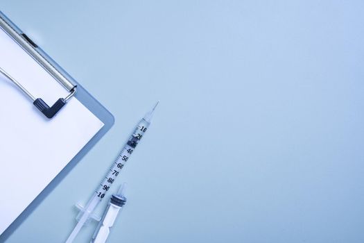 Syringes and a tablet on colored background. Medical backdrop with copy space.