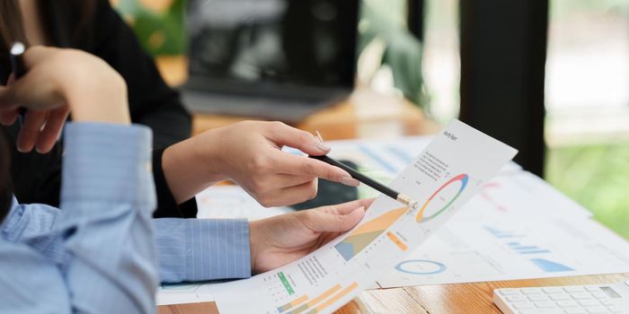 Asian Businesswoman working to analyze technical price graph and indicator with business team.