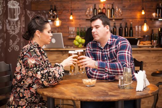 Romantic Couple drinking beer in in a hipster pub and making a toast. Cool vibe.