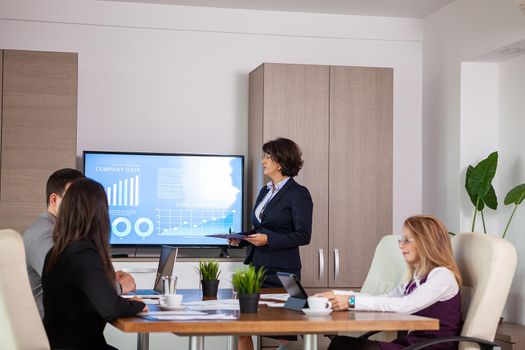 Succesful enterprenours and business people in conference room analyzing graphs and diagrams on a TV. Succesful business persons