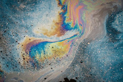 Dirty multi-colored stain from engine oil on asphalt. Environmental pollution concept.