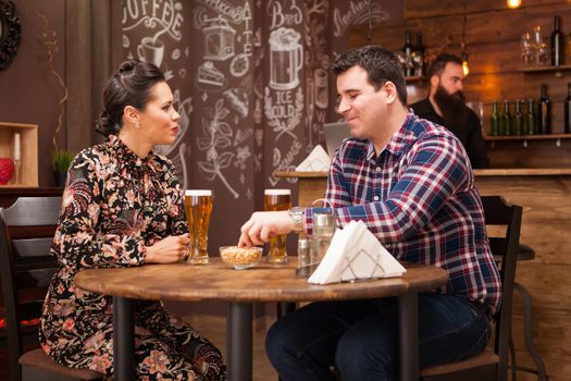 Romantic Couple drinking beer in in a hipster pub and making a toast. Cool vibe.