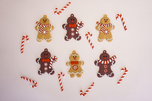 Christmas gingerbread men and caramel canes are laid out on a light background. Christmas pattern of gingerbread and canes. Beautiful Christmas picture.