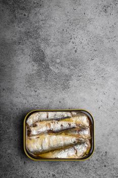 Close up and top view of canned sardine in a tin over gray concrete background, space for text. Tinned fish as a convenient, fast, healthy food and source of omega-3 fatty acids, protein and vitamin D