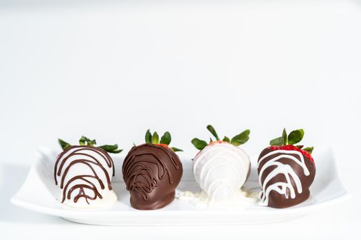White and dark chocolate dipped strawberries on a white cake stand.