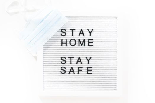 STAY HOME and STAY SAFE sign on message board with a blue medical mask.